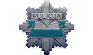 Grafika komputerowa. Policyjna, ośmioramienna gwiazda koloru srebrno-szarego. W górnej części napis Policja, poniżej wstęga koloru zielonego.
